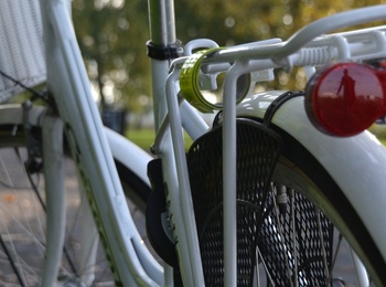 Närbild av bakdelen på en vit cykel med pakethållare och röd baklykta, utomhus på en stig.