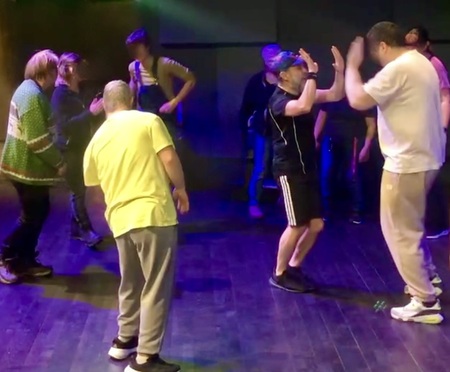 En grupp människor dansar tillsammans på ett mörkt belyst dansgolv med färgat ljus.