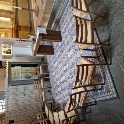 Stolar i en cirkel runt ett altare i ett kyrkorum med matta och religiösa symboler.