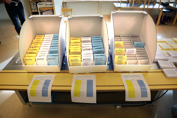 Valsedlar sorterade i lådor på ett bord i en vallokal inför ett svenskt val.