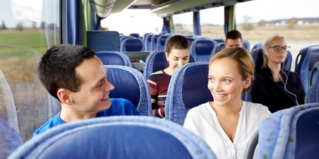 Flera personer sitter på en buss, två av dem ler och pratar med varandra.
