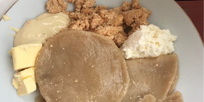 En tallrik med nigeriansk yam fufu, serverad med smör, jordnötssmulor och vit sås.