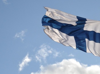 Finlands flagga vajar mot en blå himmel med några moln.