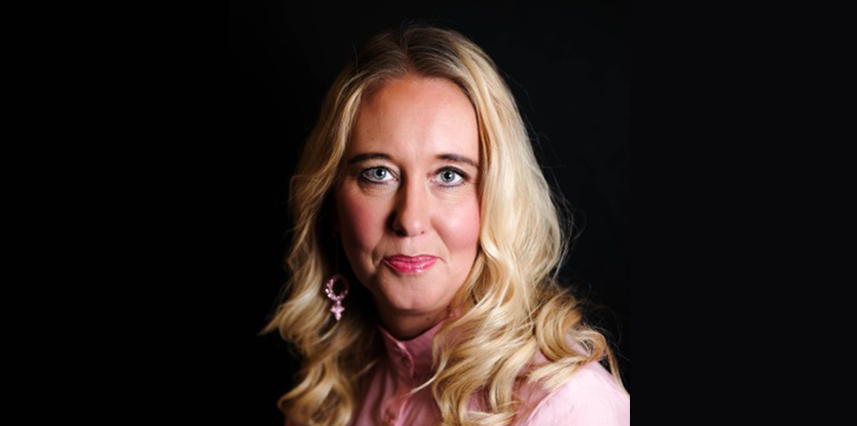 Kvinna med långt blont hår och rosa blus framför en svart bakgrund