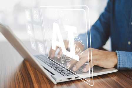 Person skriver på en bärbar dator med en digital AI-symbol på skärmen.