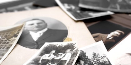 En hög med gamla svartvita fotografier, flera visar människor och familjer utomhus och inomhus.