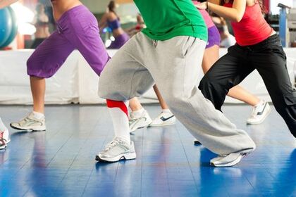 Personer i träningskläder dansar eller tränar i grupp på ett gymgolv.