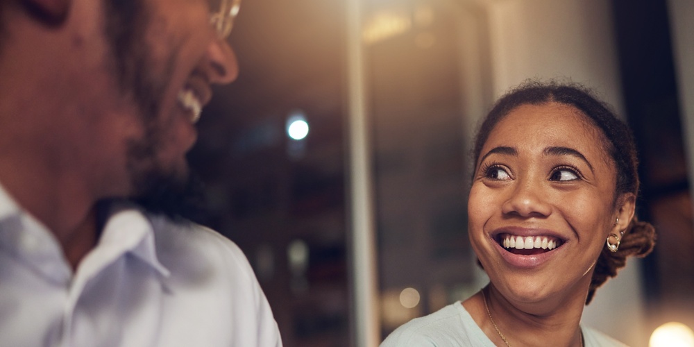 Två personer sitter och samtalar, en kvinna ler och håller i en anteckningsbok.