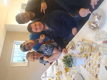 Fyra personer sitter vid ett dukat bord och äter tårta i ett ljust rum.