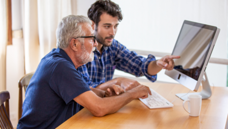 Äldre man sitter vid dator