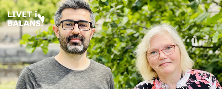 En man och en kvinna står utomhus framför gröna träd, båda bär glasögon och tittar mot kameran.