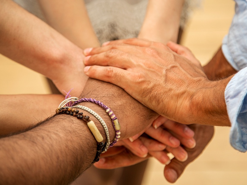 Flera händer lagda ovanpå varandra i en gest av samarbete och gemenskap.