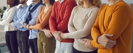 Sex personer står i rad med armarna i kors, endast överkroppar syns, i en kontorsmiljö.