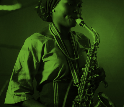 Kvinna i traditionella kläder spelar saxofon, bilden har ett grönt filter.