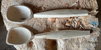 Två handgjorda träslevar ligger på en trästubbe med träspån runtom.