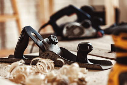 En närbild av en hyvel på ett träbord med träspån, i en snickarverkstad.