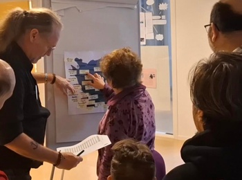 En grupp människor samlas runt en whiteboard i ett ljust rum för en gemensam diskussion.