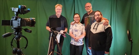 Fyra personer står framför en grön bakgrund i en studio med kamera och utrustning.