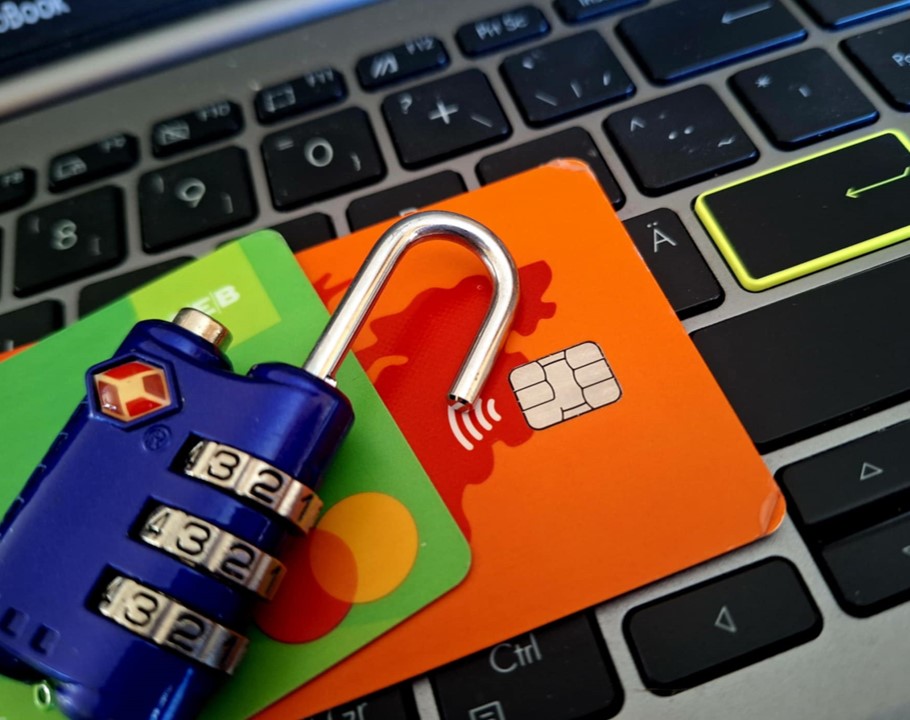 Ett öppet hänglås, två bankkort och ett tangentbord, symboliserar datasäkerhet och bankbedrägeri.
