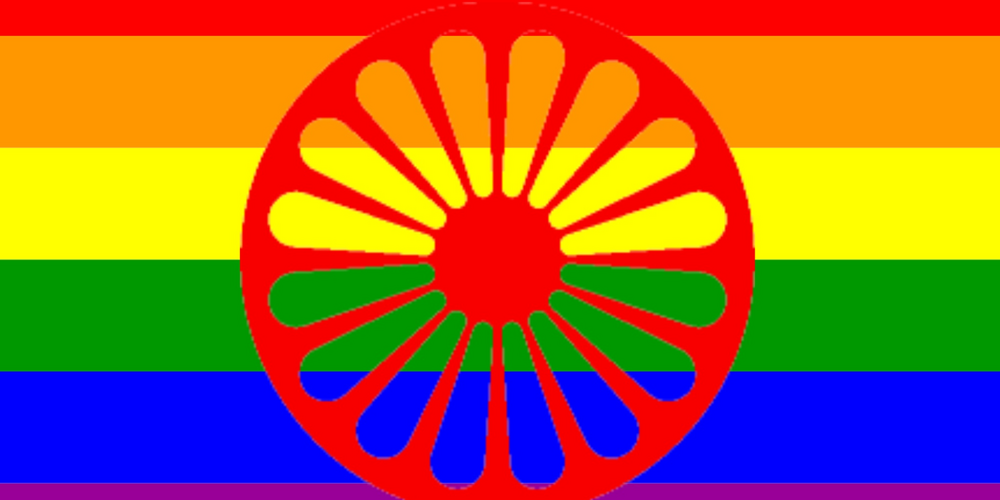 En flagga med regnbågsfärger och ett rött hjul i mitten, symbol för romer och HBTQ+ gemenskap.