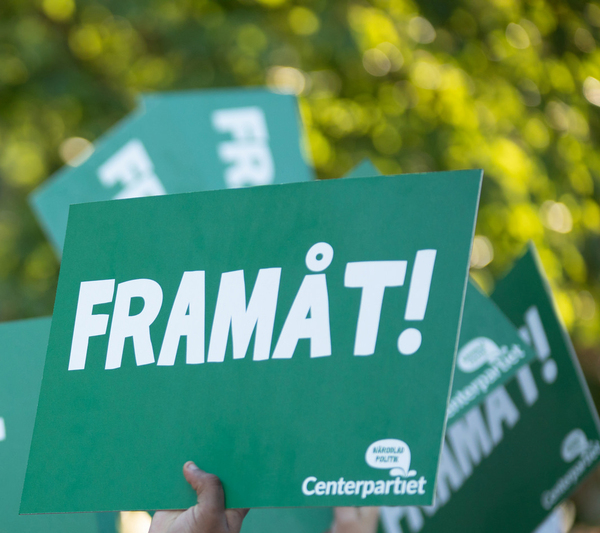 En grupp gröna valskyltar för Centerpartiet med ordet Framåt på uppsträckta i luften.