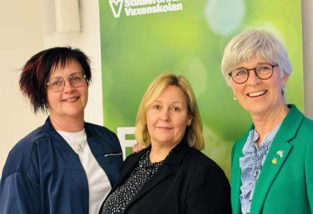 Tre kvinnor står framför en grön skylt med texten 'Studieförbundet Vuxenskolan'.