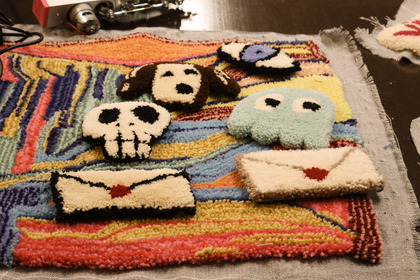Färgglad matta med tuftade figurer som hund, dödskalle, spöke, öga och kuvert med hjärta.
