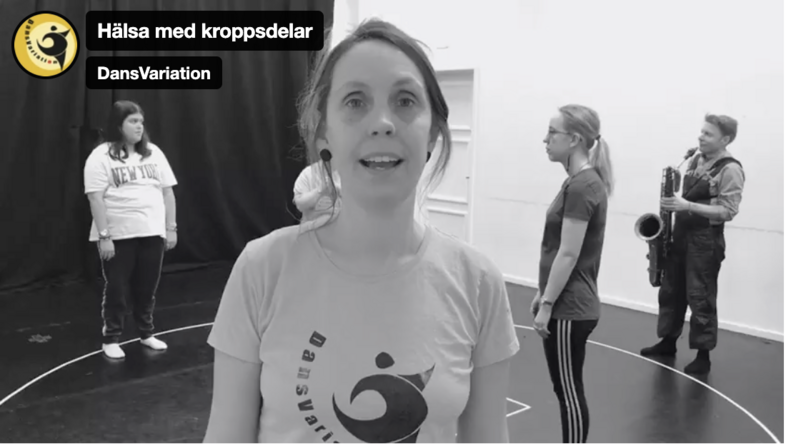 Fyra personer står i en danssal, en spelar saxofon. Text: Hälsa med kroppsdelar, DansVariation.