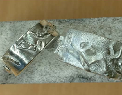 Två silverringar med handgjorda mönster ligger på en grå sten.