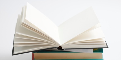 En hög med böcker där den översta boken är uppslagen och resten är stängda, mot vit bakgrund.