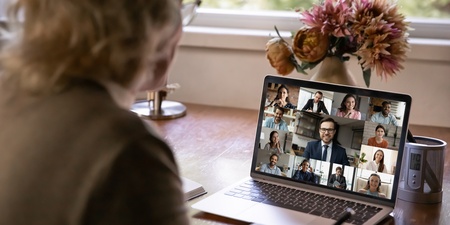 En person deltar i ett videomöte med flera deltagare på en bärbar dator vid ett skrivbord.