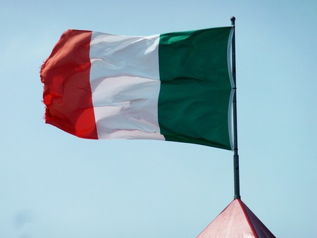 Den italienska flaggan vajar mot en klarblå himmel ovanpå en flaggstång.