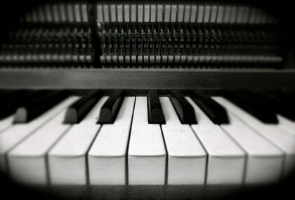 Närbild av pianotangenter i svartvitt, med pianots mekanik synlig ovanför tangenterna.