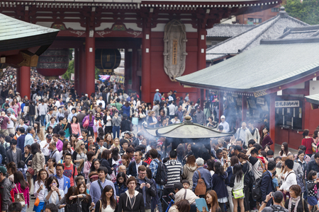 Stor folkmassa samlad vid ett tempel i Japan, med rök från en rökelsebrännare i förgrunden.