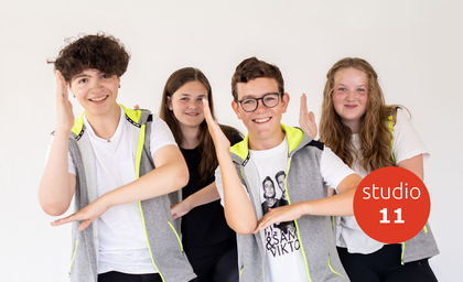 Fyra ungdomar poserar glatt mot kameran, två av dem gör tecken med armarna. Texten 'studio 11' syns i röd cirkel.