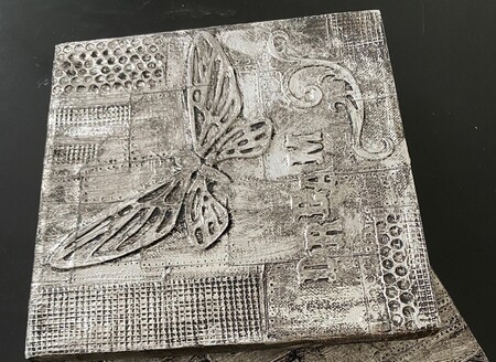 Dekorativt konstverk med fjäril, texten 'DREAM' och olika mönster i svartvitt.