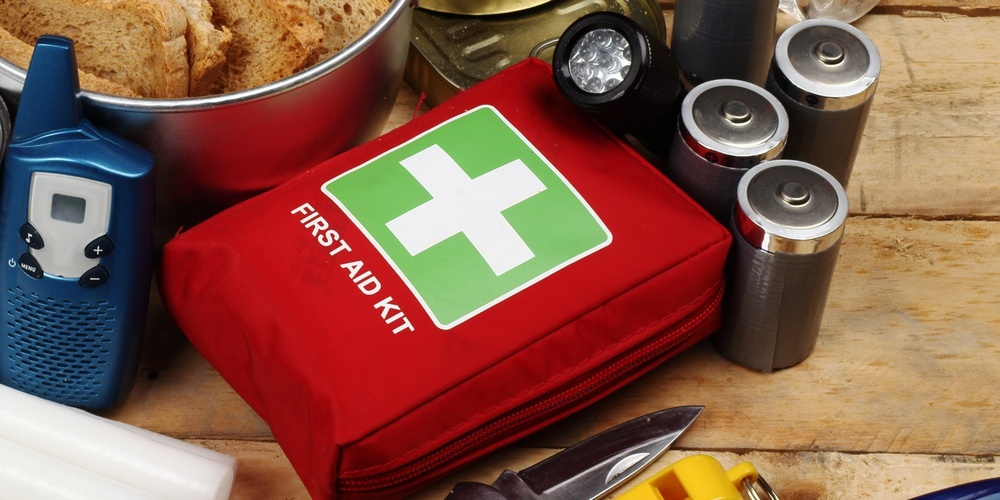 Nödutrustning med första hjälpen-kit, kniv, ljus och på ett träbord.