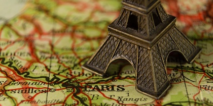 Närbild av en liten Eiffeltorn-modell placerad på en karta över Paris, Frankrike.