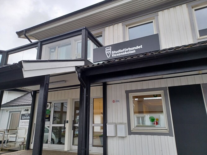 Entré till en vit byggnad med skylt för Studieförbundet Vuxenskolan ovanför dörren.