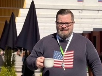 man som går utomhus med kaffekopp i handen och nycklar runt halsen