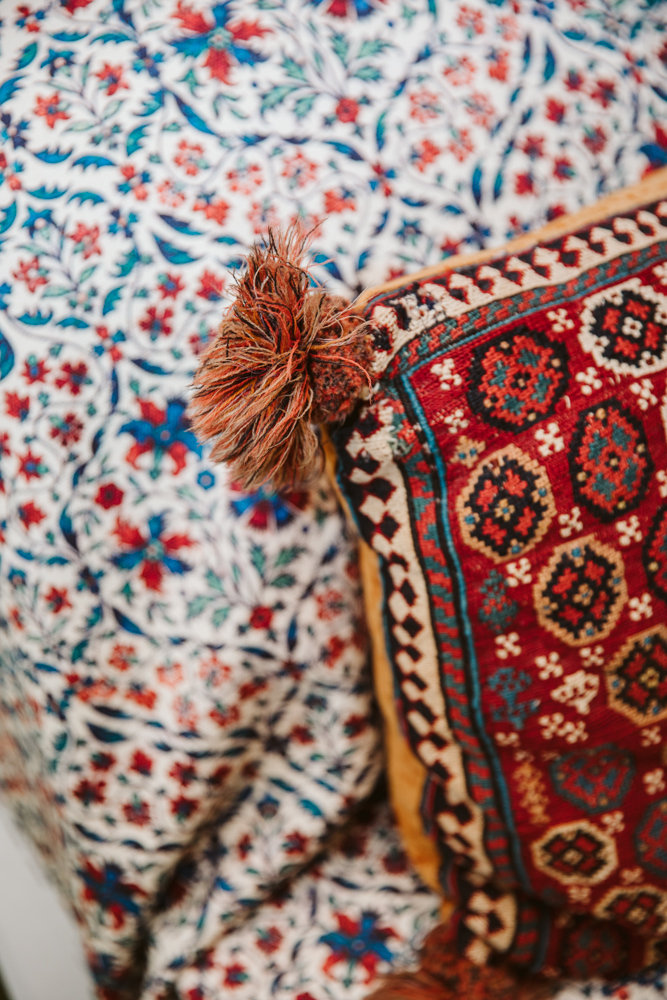 Närbild av en kudde med orientaliskt mönster mot ett blommigt tyg i bakgrunden.