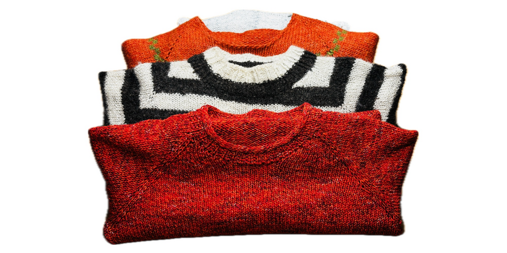 Tre vikta stickade tröjor i rött, svartvitt och orange ligger staplade på varandra mot vit bakgrund.