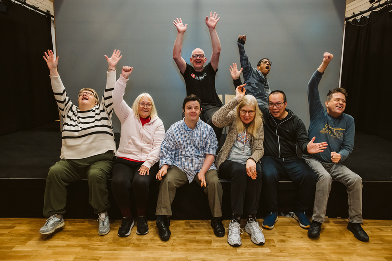 Åtta personer är samlade på en scen och jublar