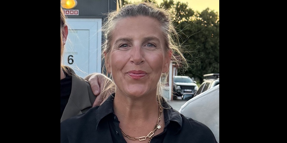 Person i svart skjorta och guldhalsband står utomhus, ansiktet är suddat för anonymitet.