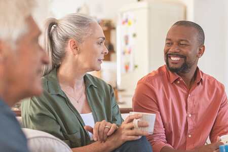 Tre personer sitter och samtalar med varandra i en soffgrupp.