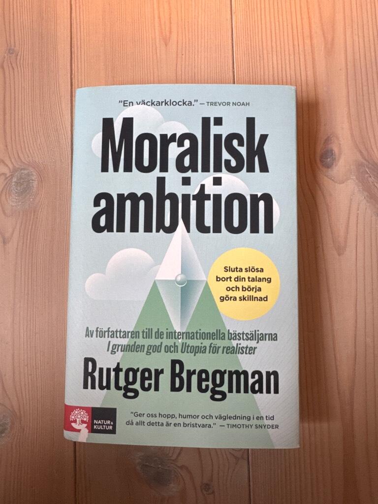 Bokomslag till 'Moralisk ambition' av Rutger Bregman på ett trägolv.