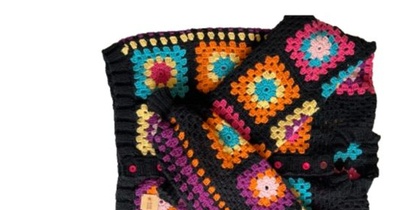 Färgglad virkad filt med mormorsrutor i olika färger på svart bakgrund.