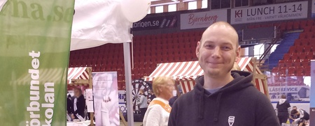 Man står vid informationsbord för Studieförbundet Vuxenskolan på en mässa inomhus.