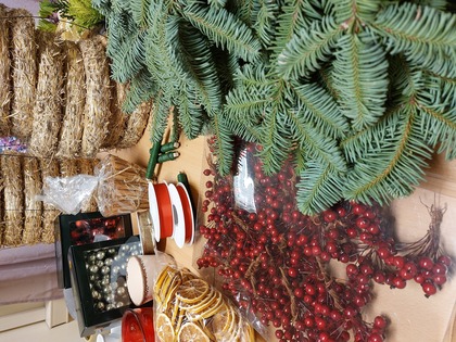 Material för att göra julkransar, inklusive granris, halmstommar, röda bär, torkade apelsiner, kanelstänger och julkulor.