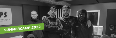 Fyra unga män står tillsammans i en musikstudio med texten 'Summercamp 2022' över bilden.